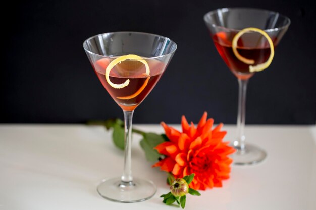 Foto close-up de bebidas alcoólicas com flor na mesa contra fundo preto