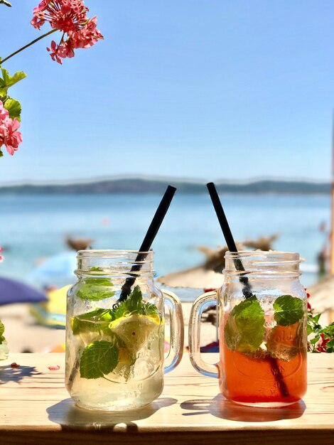 Close-up de bebidas na mesa na praia contra o céu claro