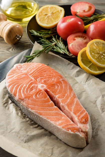 Close-up de bife de peixe vermelho cru. Posta de salmão em papel de embrulho com ingredientes para cozinhar.