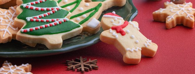 Close-up de biscoitos de açúcar decorados de Natal em um prato no fundo da mesa vermelha