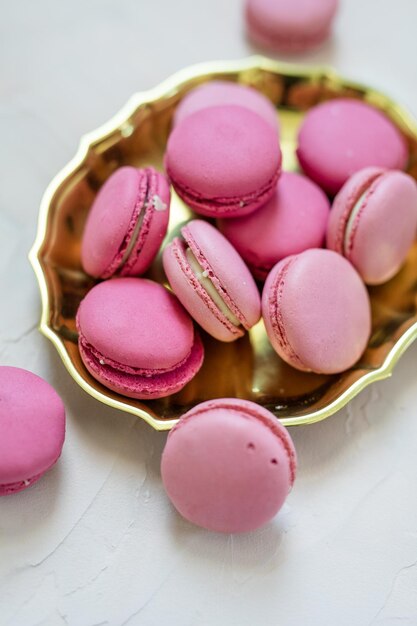 Close-up de biscoitos de macarrão rosa em placa de ouro com fundo branco