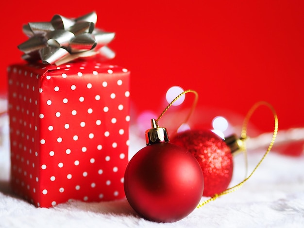 Close-up de bolas vermelhas por presentes de Natal em tapete branco