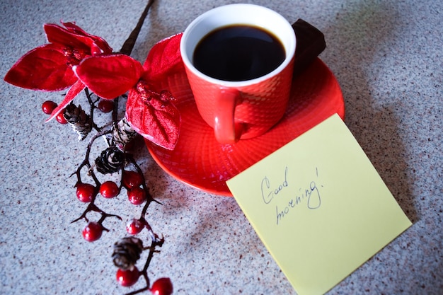 Foto close-up de café preto com bagas vermelhas e nota na mesa