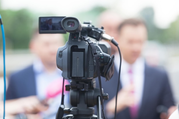 Close-up de câmera de televisão com um empresário ao fundo