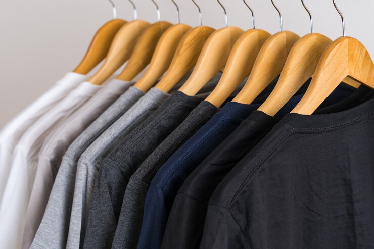 Foto close-up de camisetas em cabides, fundo de vestuário