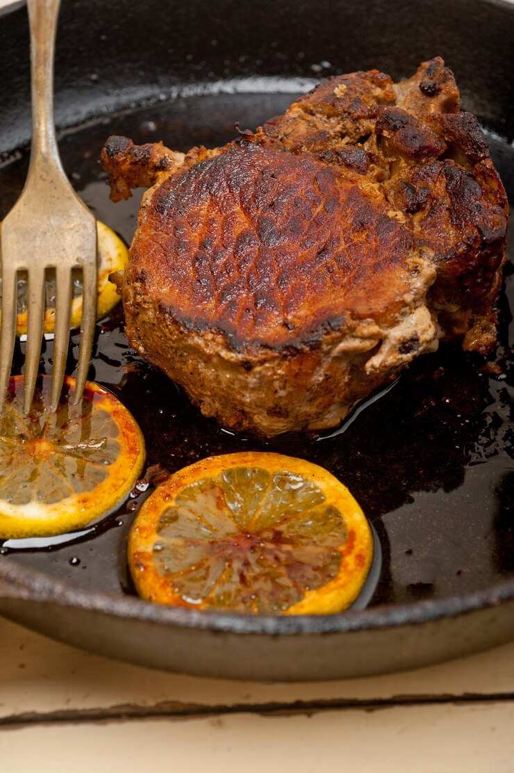 Foto close-up de carne com fatias de limão na frigideira na mesa