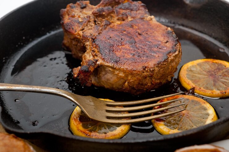 Foto close-up de carne com fatias de limão na frigideira na mesa