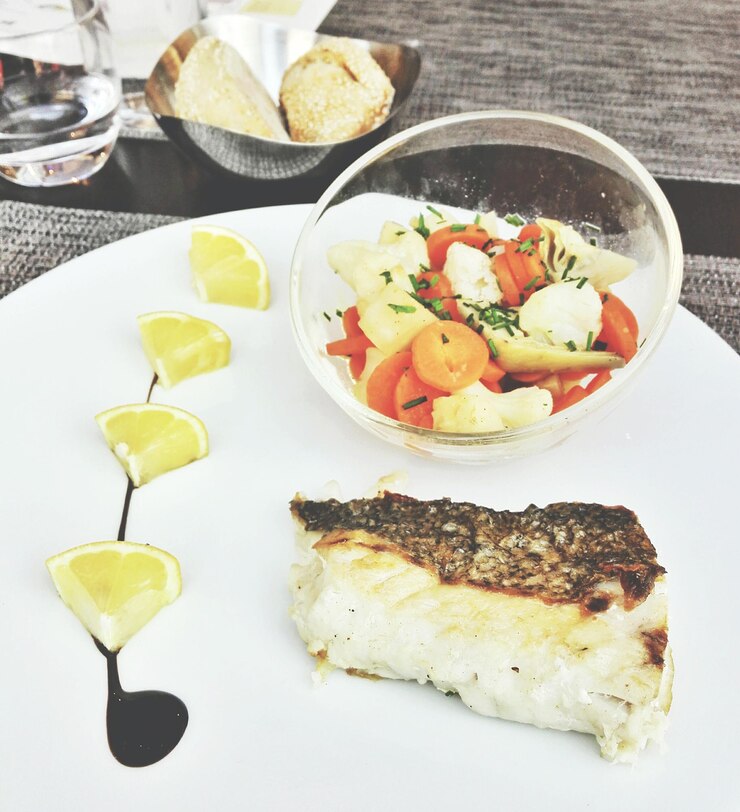 Foto close-up de carne de peixe com salada e fatias de limão em prato