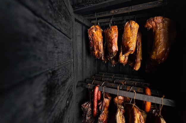 Close-up de carne defumada e barriga ou carne de faia com crosta escura no fumeiro ou fum...