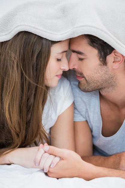 Close-up de casal namorando sob o cobertor na cama