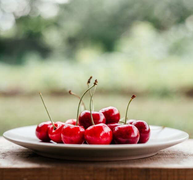 Foto close-up de cereja doce madura em fundo bokeh verde verão, frutas de verão com alto teor de vitaminas e antioxidantes