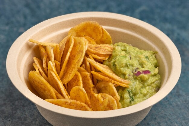 Close-up de chips de banana frita com guacamole caseiro.