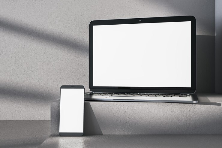 Foto close-up de computador portátil branco vazio e telefone em mesa cinza sombras de fundo de parede de concreto e pedestal ou pódio presentação de dispositivo e conceito de educação on-line renderização 3d