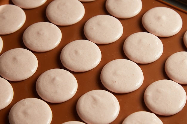 Close-up de conchas de macaroon francês na esteira de cozimento. Textura e padrão.