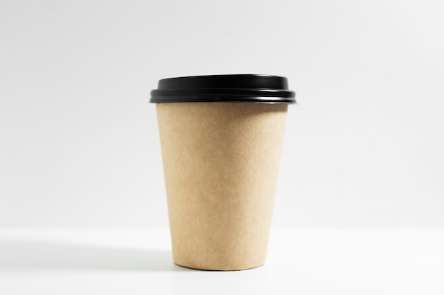Close-up de copo de papel descartável para levar para café, com tampa preta, isolado no branco.