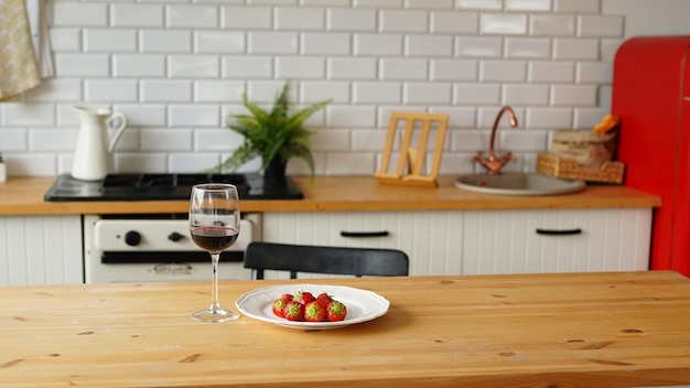 Close-up de copo de vinho com morangos no prato na mesa na cozinha Conceito de namoro