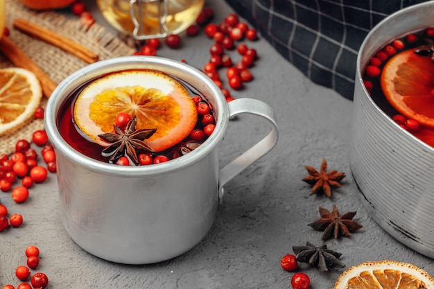 Close-up de copo de vinho quente com especiarias e frutas na mesa cinza