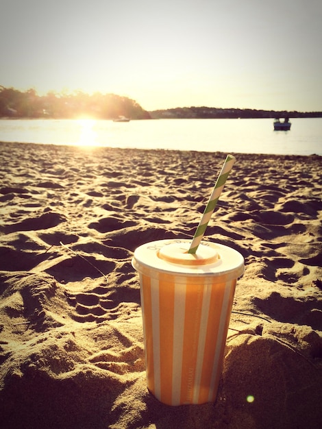 Foto close-up de copo descartável na areia na praia