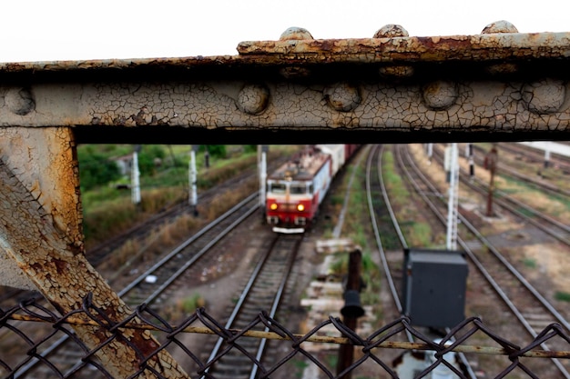 Foto close-up de corrimão metálico enferrujado de ponte sobre trilhos ferroviários