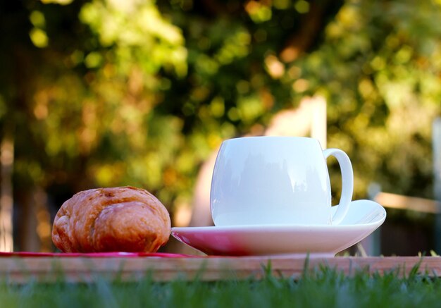 Close-up de croissant e xícara de chá na prancha de corte