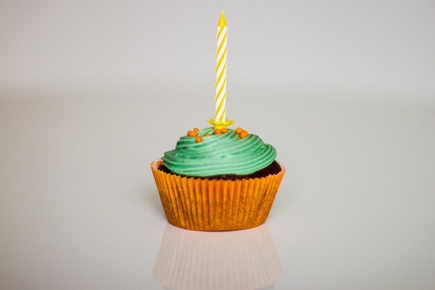 Close-up de cupcakes com vela de aniversário contra fundo branco