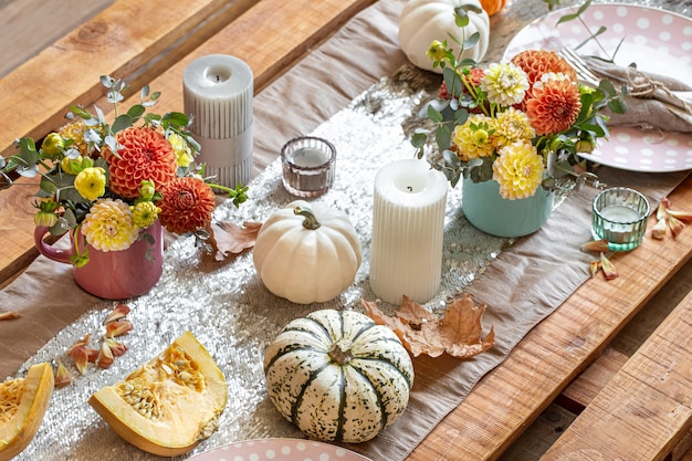 Close-up de detalhes de decoração aconchegante de uma mesa de jantar festiva de outono com abóboras, flores e velas.