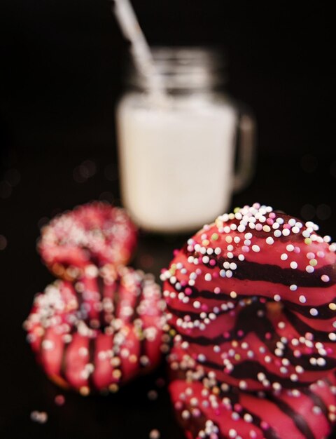 Foto close-up de donuts coloridos e leite em fundo preto