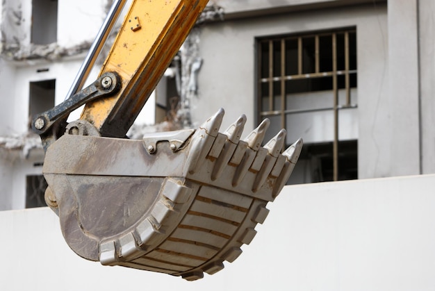 Foto close-up de escavadeira grader tractor balde edifício arruinado no fundo