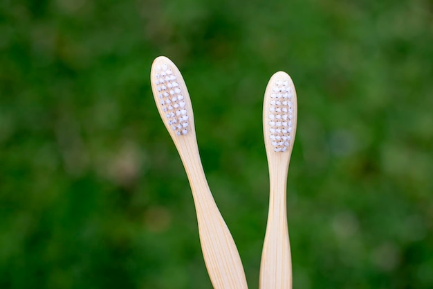 Close-up de escovas de dentes de bambu com fundo de grama verde escovas de dentes de bambu biodegradáveis