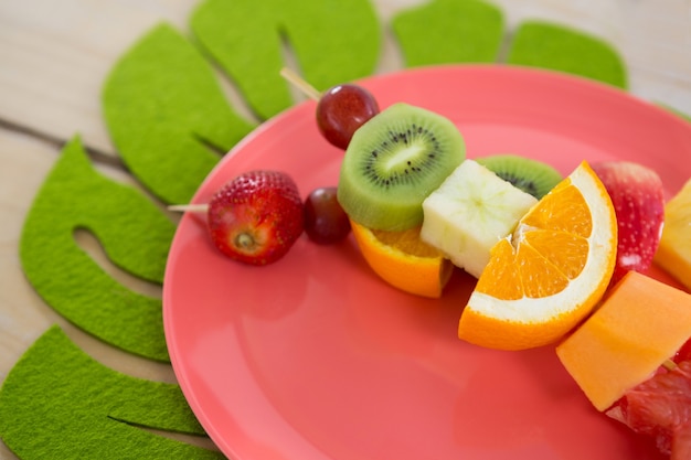 Close-up de espetos de frutas no prato na mesa de madeira