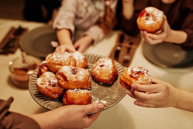 Close-up de família acolhedora com crianças desfrutando de pastelaria caseira na mesa de jantar