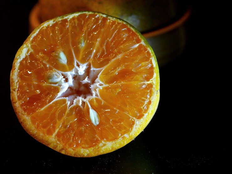 Foto close-up de fatia de laranja contra fundo preto