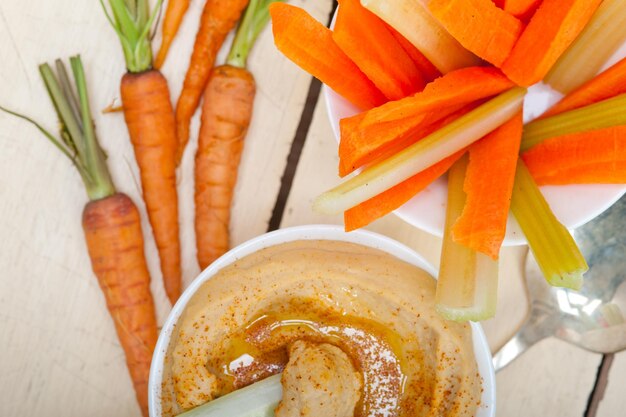 Foto close-up de fatias de vegetais de raiz com molho de húmus na mesa