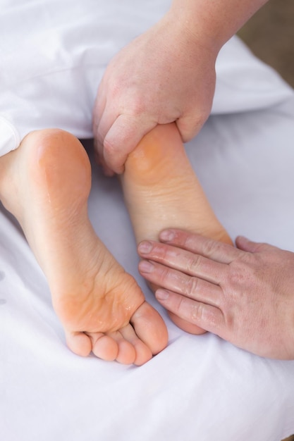 Foto close-up de fisioterapeuta dando a um paciente um tratamento de massagem dos pés massagem reflexológica dos pés vertical