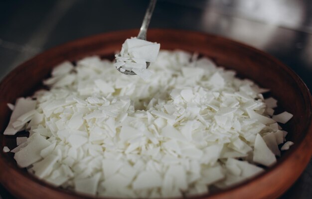 Close-up de flocos de cera de soja branca para fazer velas em uma tigela de cerâmica