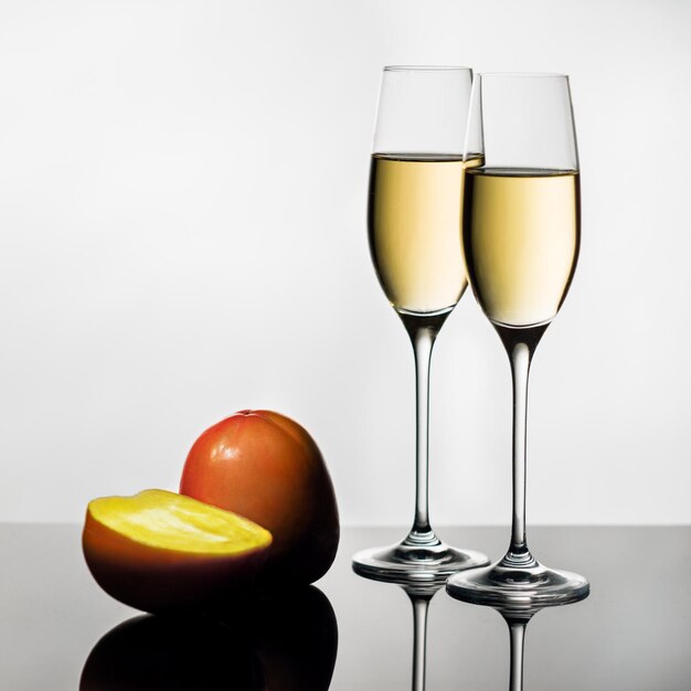 Foto close-up de frutas com vinho branco em mesa de vidro contra fundo branco