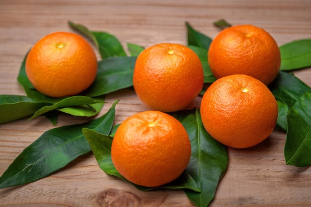 Close-up de frutas laranja tangerina com folhas em cima da mesa