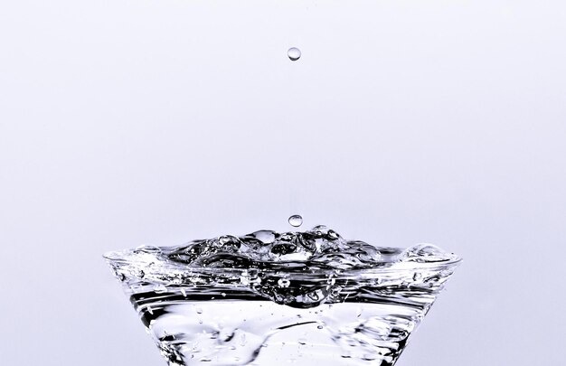 Close-up de gota de água caindo em um copo.