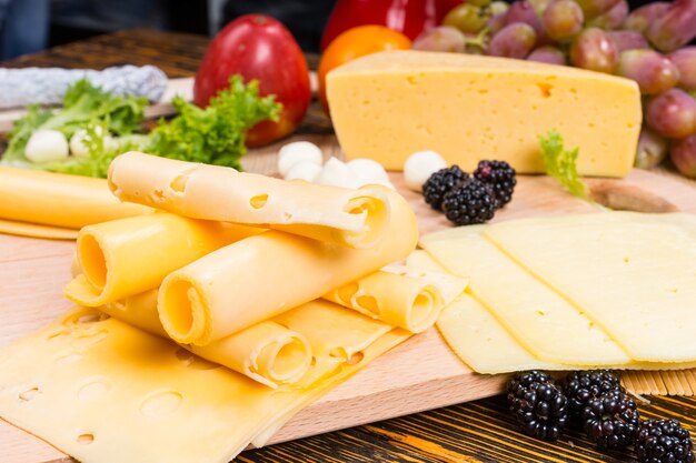 Close Up de Gourmet Cheese Board Aperitivo com Fatias de Queijo Suíço Enrolado e Guarnecido com Frutas Frescas