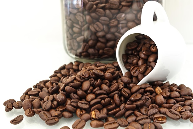 Close-up de grãos de café torrados com jarro e jarro contra fundo branco