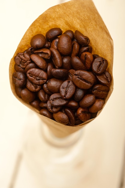 Foto close-up de grãos de café torrados em papel marrom sobre a mesa