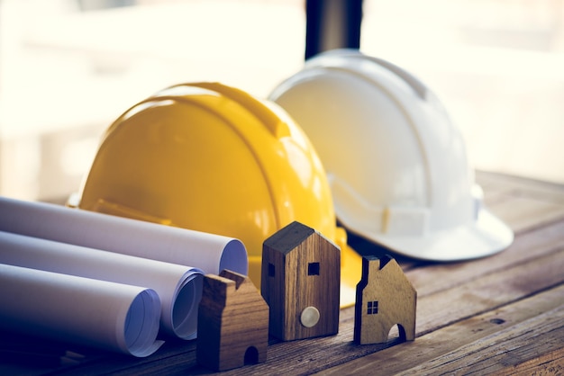 Close-up de hardhats por planos e casas modelo em mesa por janela