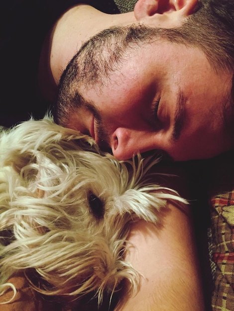 Foto close-up de homem e cachorro dormindo na cama