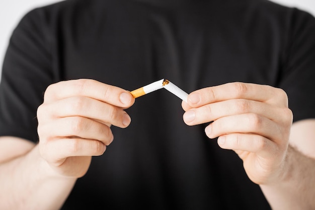 close-up de homem quebrando o cigarro com as mãos