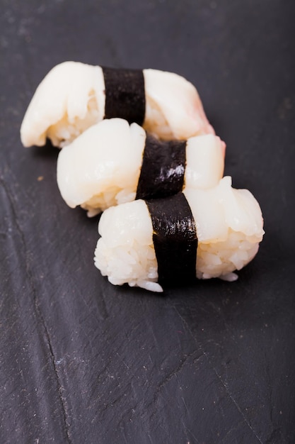 Close-up de Hotate nigiri sushi com vieira em um fundo de ardósia preta
