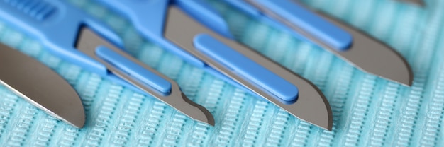 Close-up de instrumentos cirúrgicos na sala de operações no envoltório esterilizado azul. Facas diferentes para intervenção cirúrgica. Ferramentas clínicas profissionais. Conceito de ambulância de cirurgia médica