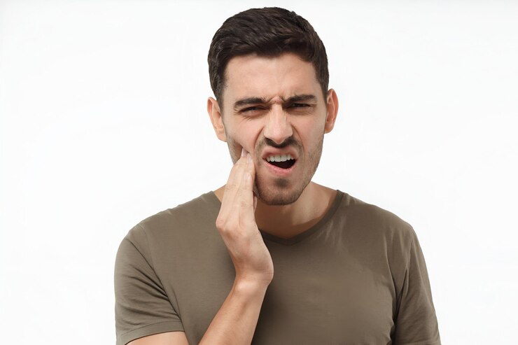 Foto close-up de jovem isolado em fundo cinza tocando seu rosto e fechando os olhos com expressão de horrível sofrer de problema de saúde e dor de dente