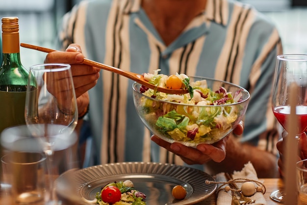 Close-up de jovem segurando a tigela de salada enquanto desfruta de um jantar no espaço de cópia de ambiente aconchegante