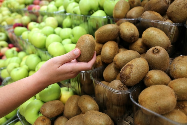 close-up de kiwis orgânicos e frescos selecionados pelo cliente no supermercado