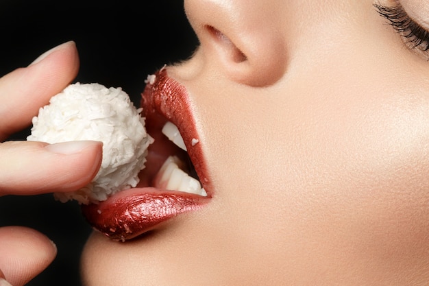 Foto close-up de lábios femininos comendo doce de coco